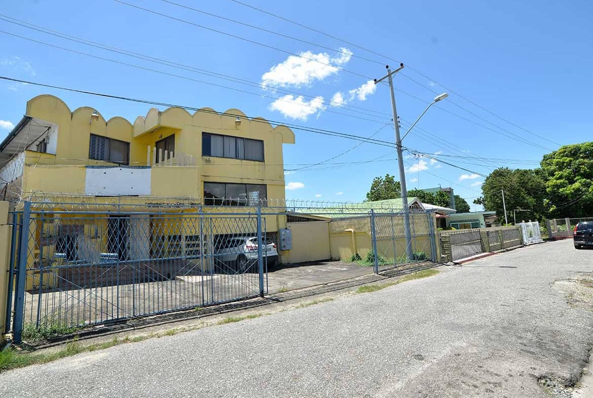Cornerstone- Commercial building on Sellier Street, Curepe with yellow facade and gated parking.