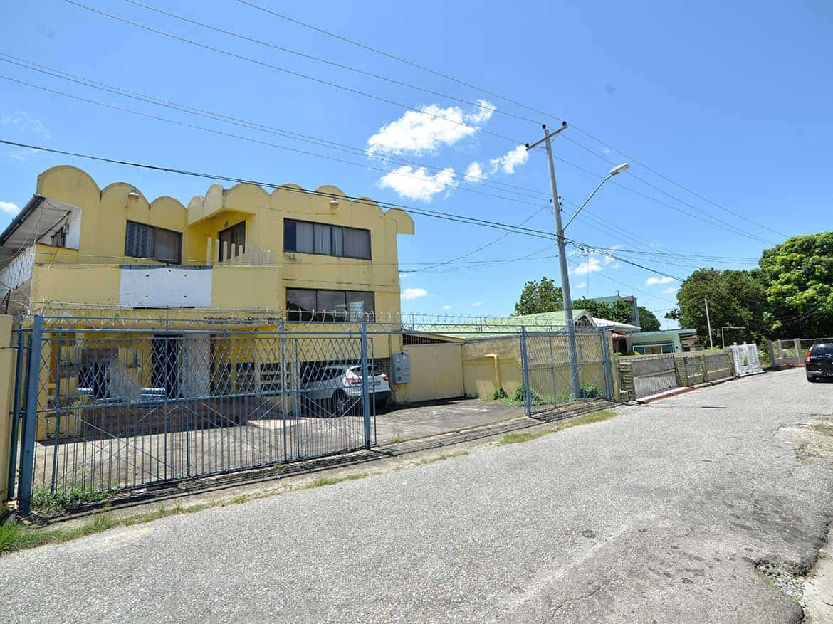 Sellier Street, Curepe Commercial Building Cornerstone- Commercial building on Sellier Street, Curepe with yellow facade and gated parking.