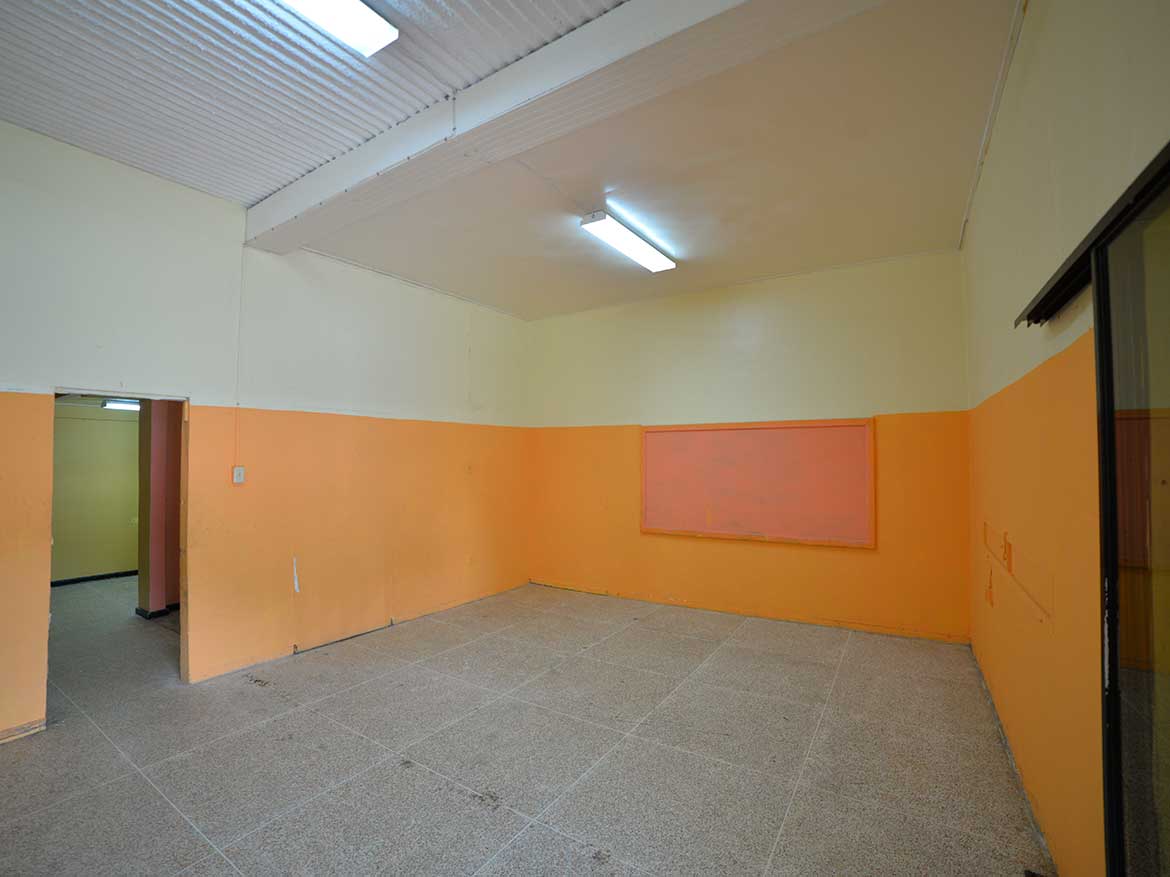 Cornerstone™ Sellier Street, Curepe Cornerstone- Empty room with orange walls and fluorescent lighting in Curepe.