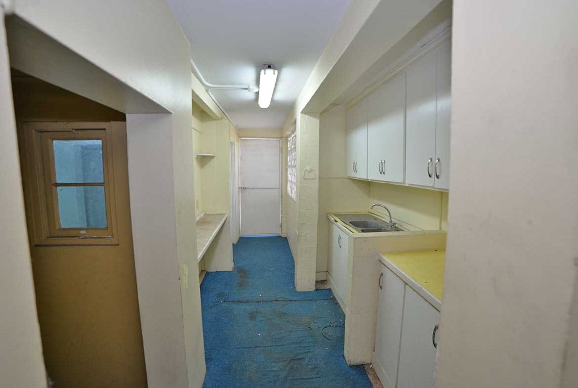 Cornerstone- Small kitchen with white cabinets and blue flooring in Curepe.