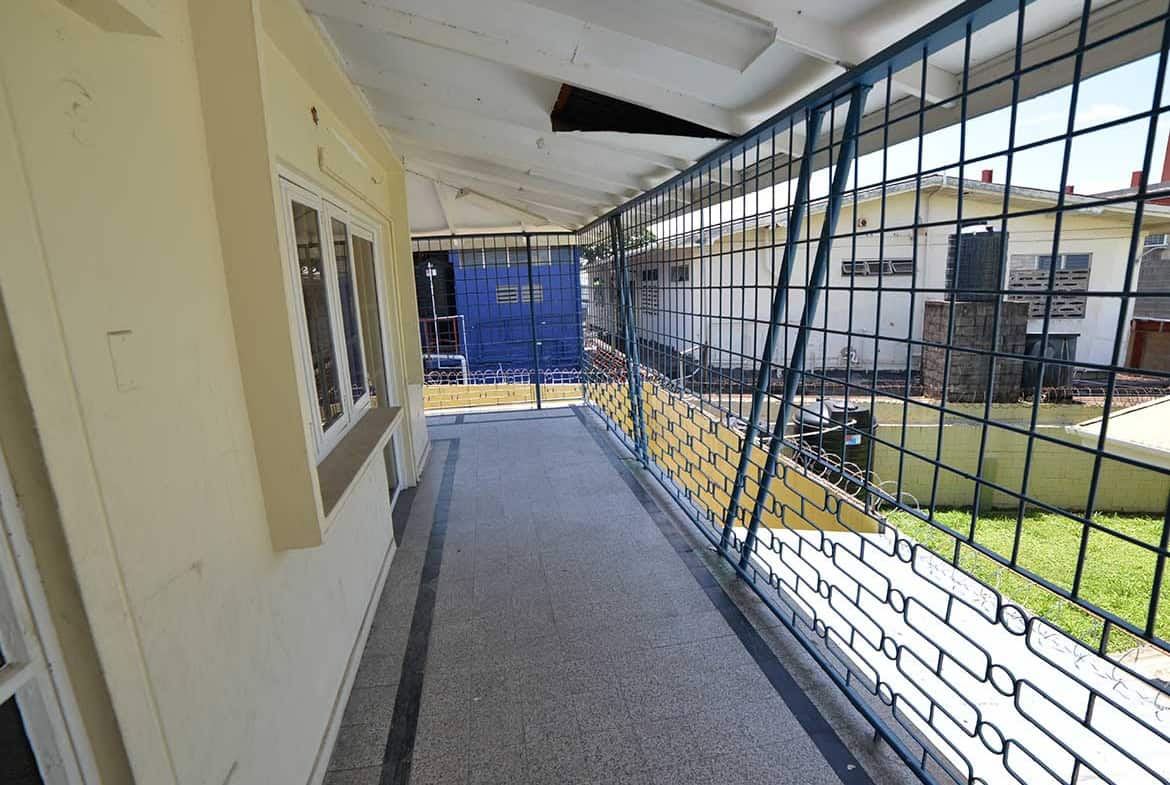 Cornerstone- Balcony with safety grill overlooking neighboring buildings and yard.
