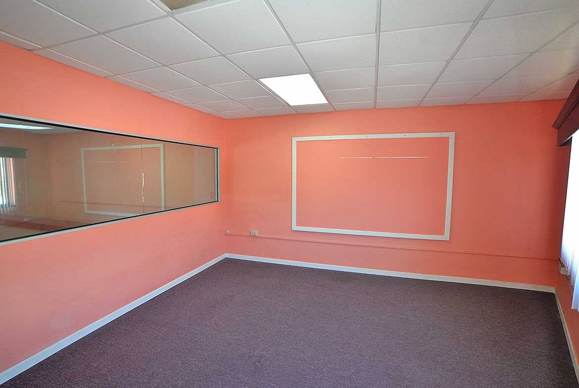 Cornerstone- Empty office room with pink walls and large window in Curepe.