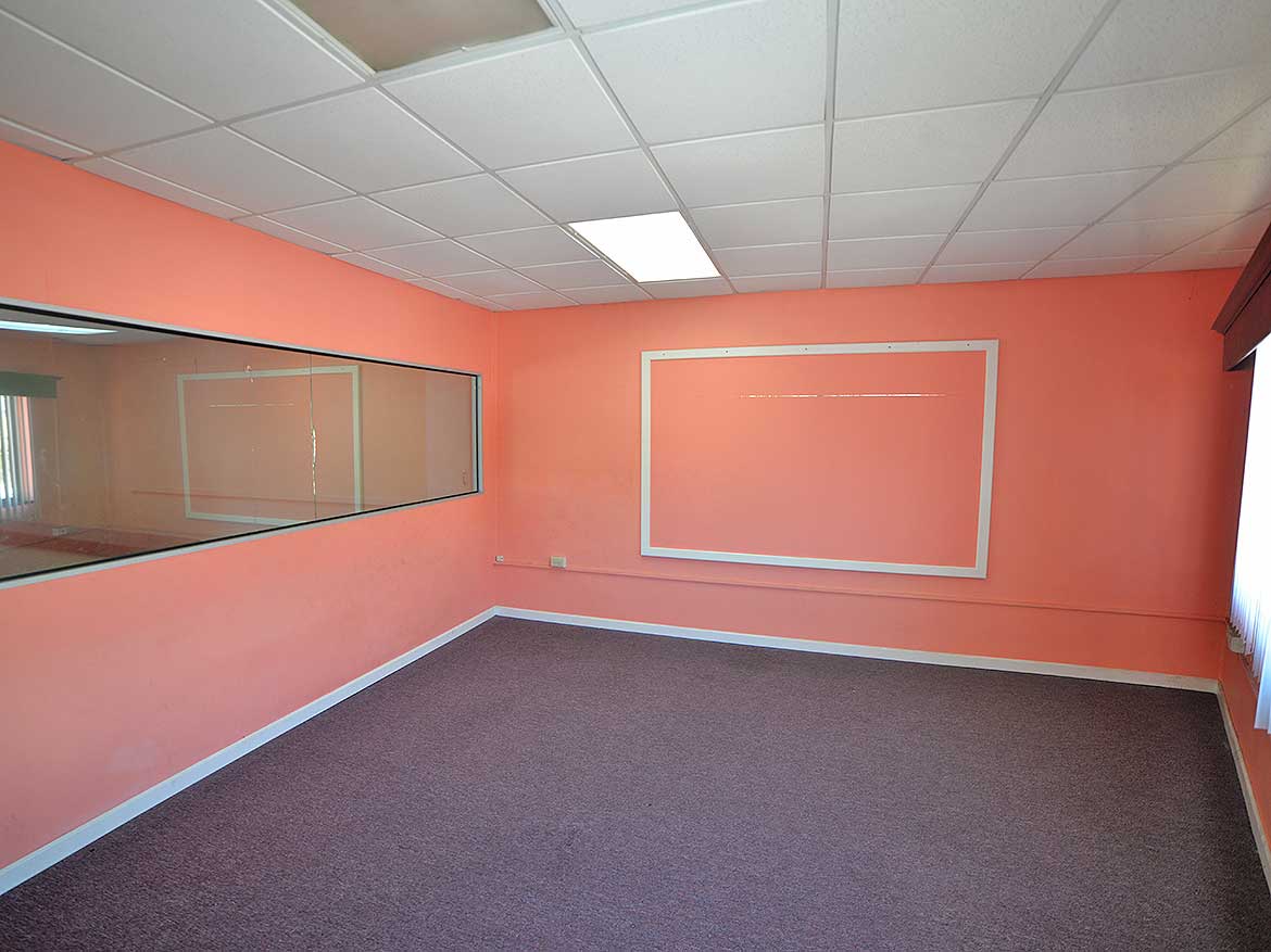 Cornerstone™ Office Space in Curepe Cornerstone- Empty office room with pink walls and large window in Curepe.