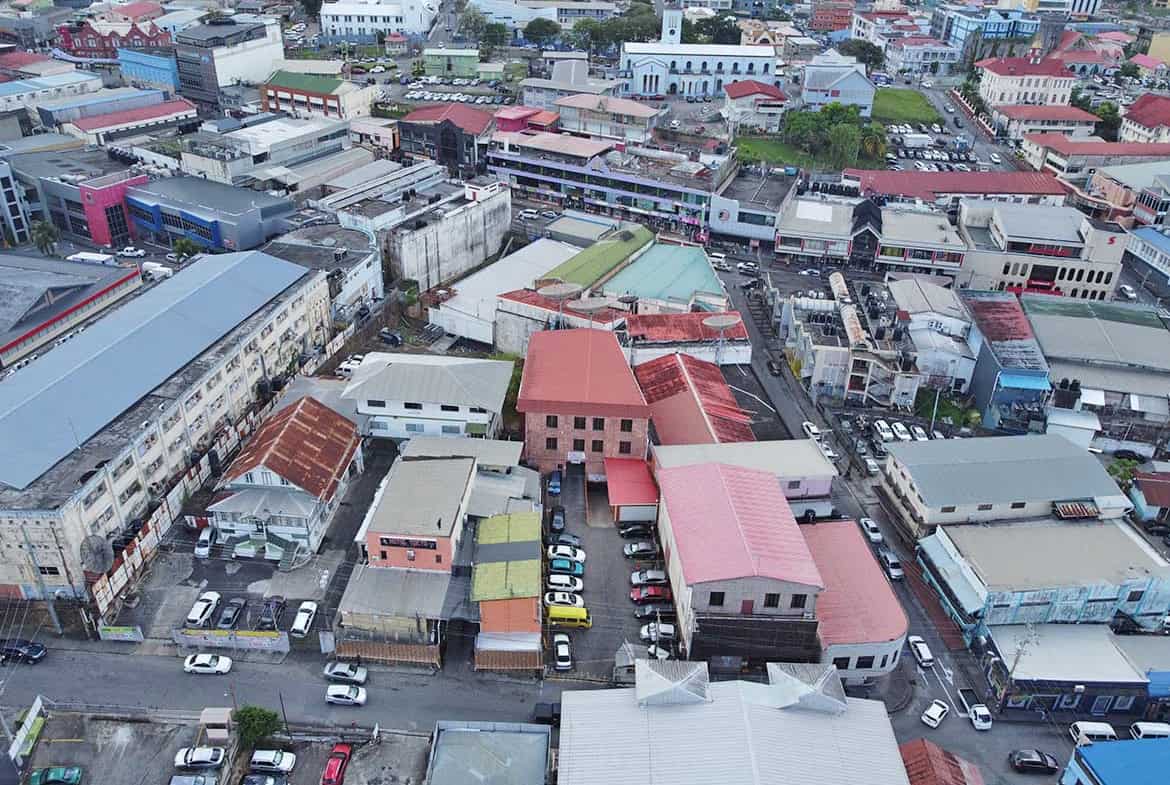 Cornerstone- Aerial view of St James Street with shops and parking lots in Port of Spain.
