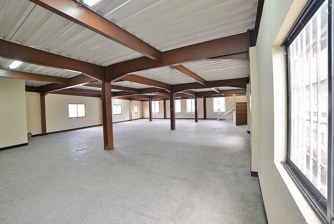 Cornerstone- Open interior of commercial property with large windows and steel beams.