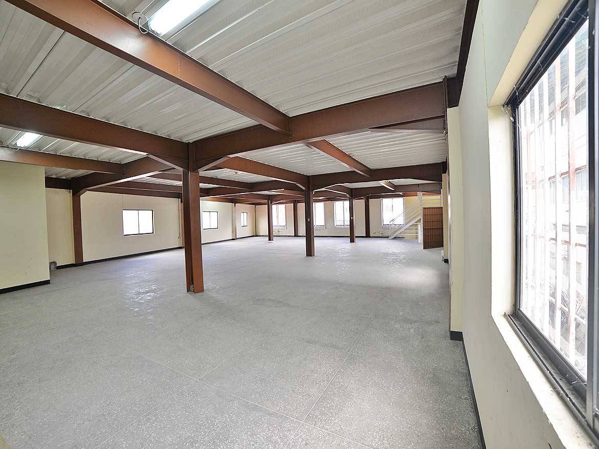 Spacious Commercial Space on St James Street Cornerstone- Open interior of commercial property with large windows and steel beams.