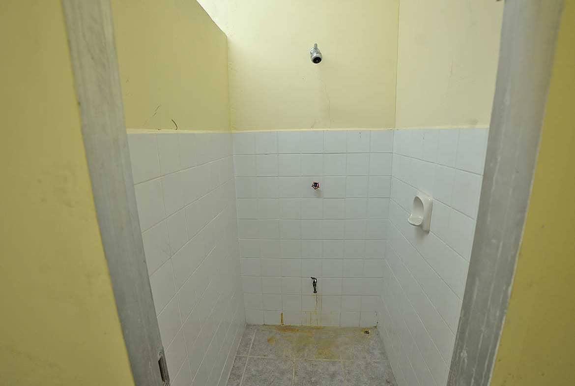 Cornerstone- Empty restroom with white tiled walls and yellow painted walls.