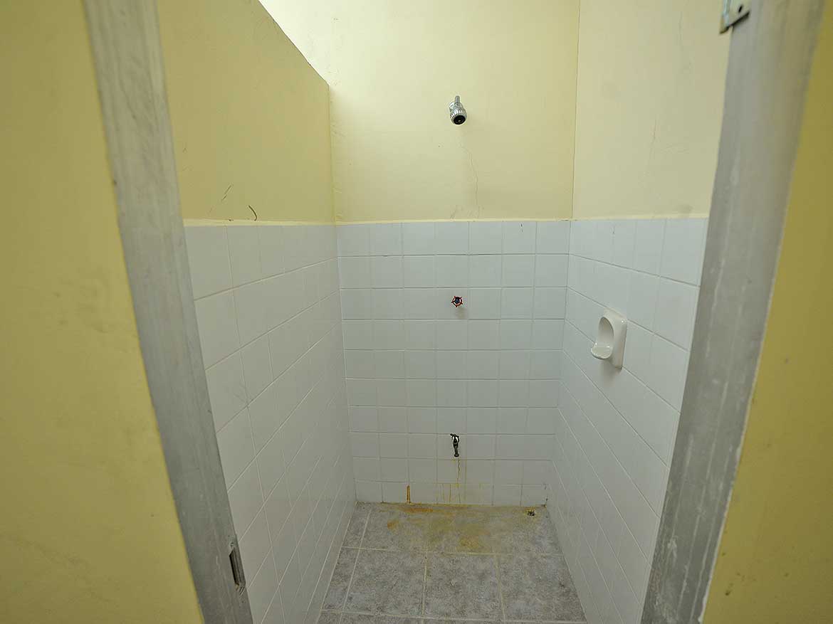 St James Street Restroom Renovation Cornerstone- Empty restroom with white tiled walls and yellow painted walls.