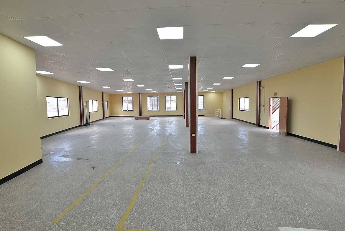 Cornerstone- Large empty commercial space with high ceilings and multiple windows.
