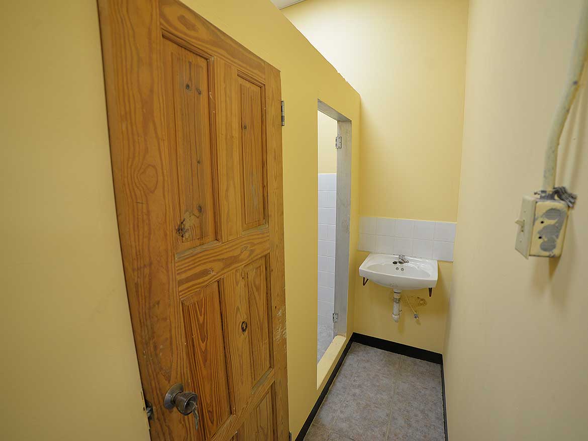 Cornerstone™ Restroom on St James Street Cornerstone- Small restroom with wooden door and wall-mounted sink in St James Street building.