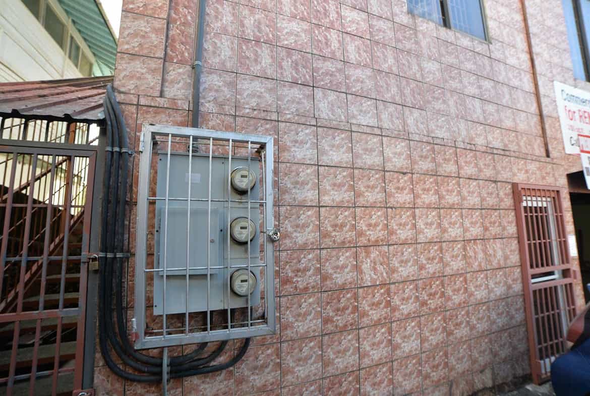 Cornerstone- Close-up of building exterior wall with electrical meter box and wiring.