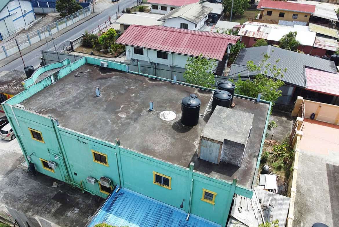 Cornerstone- Aerial view of a building rooftop with water tanks and surrounding neighborhood.