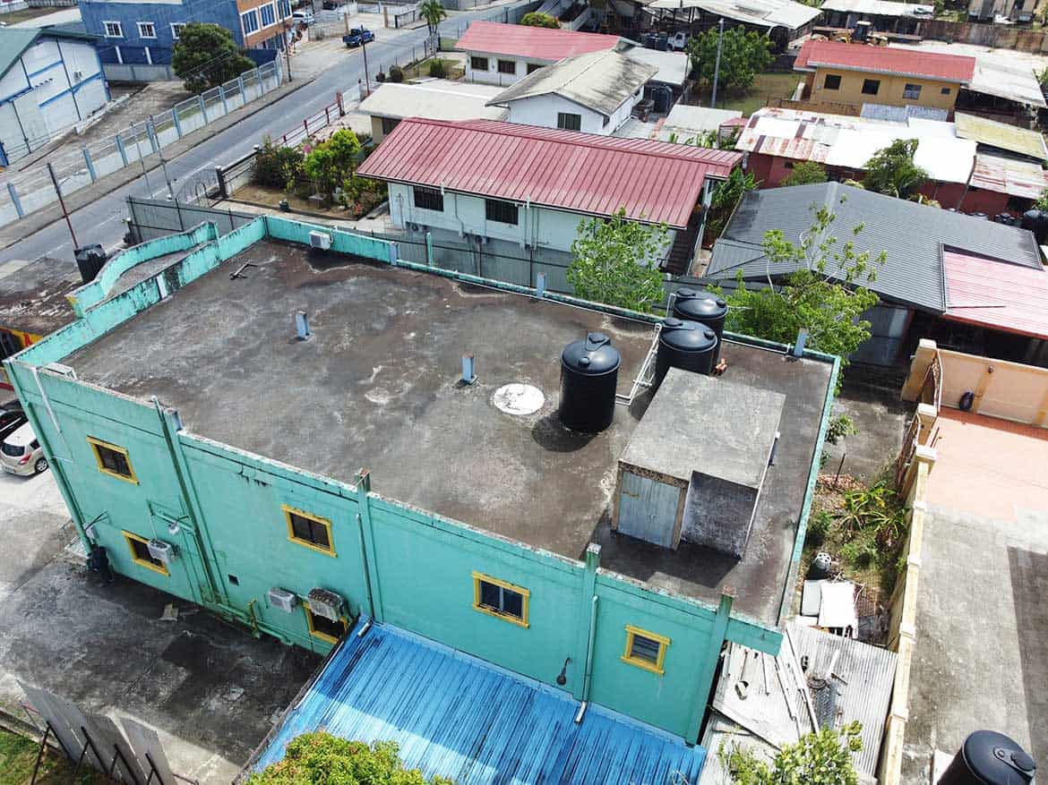 Urban Rooftop with Water Tanks Cornerstone- Aerial view of a building rooftop with water tanks and surrounding neighborhood.