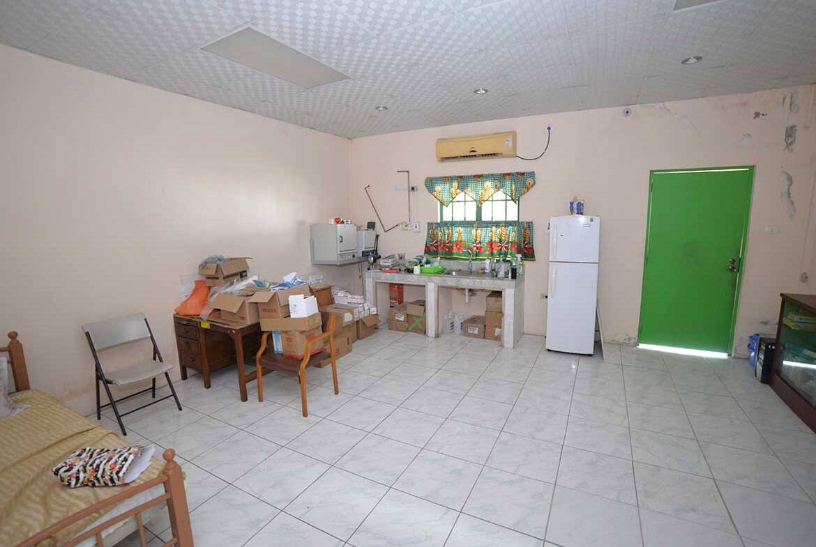 Cornerstone- Simple room with furniture, boxes, and a green door.