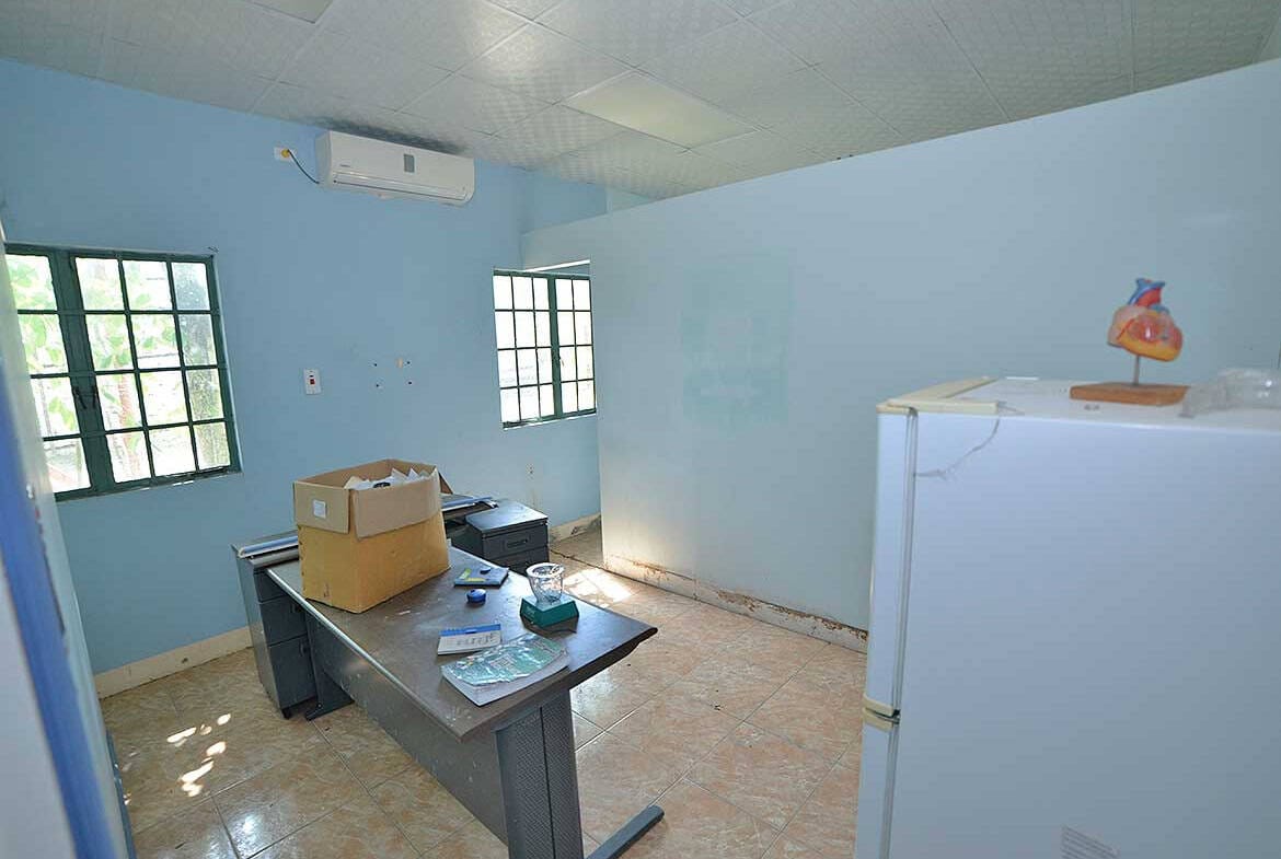 Cornerstone- Small office room with blue walls, windows, and a desk with items.