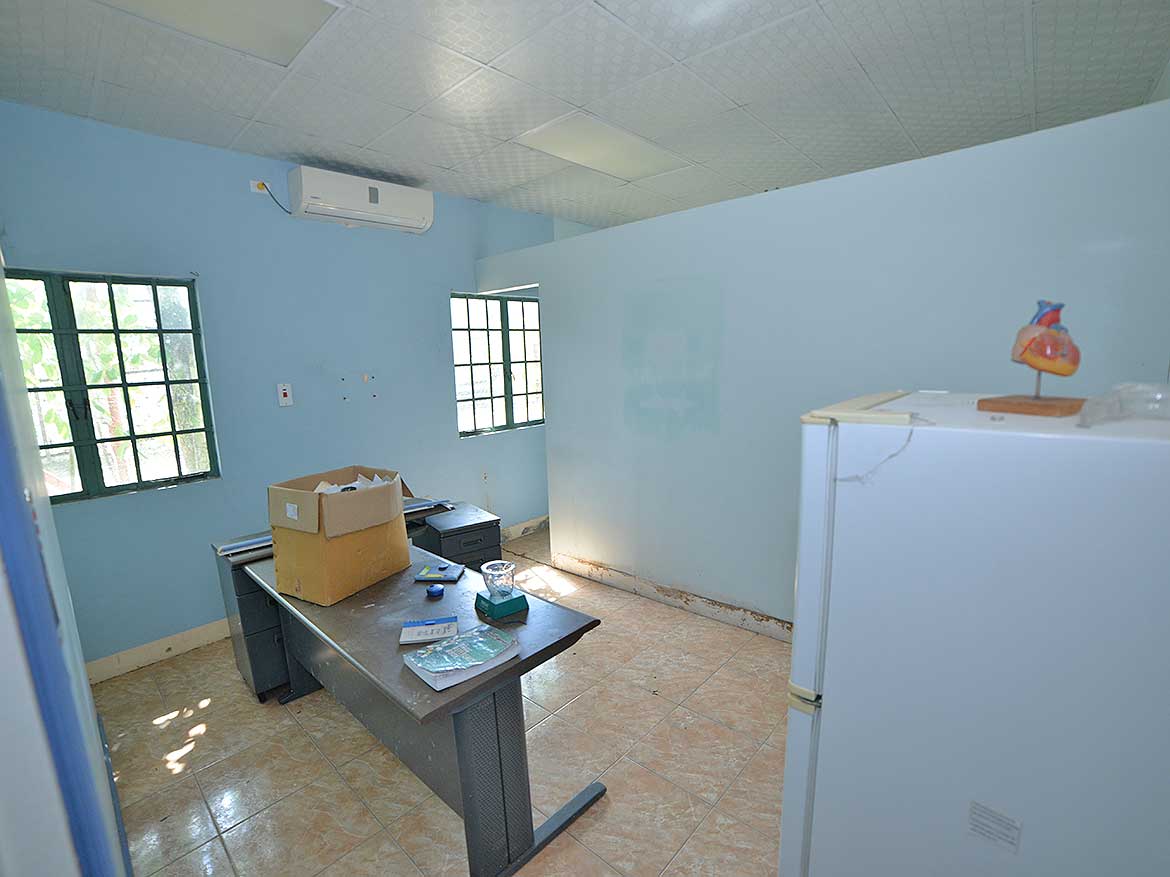 Interior of a Small Office Room Cornerstone- Small office room with blue walls, windows, and a desk with items.