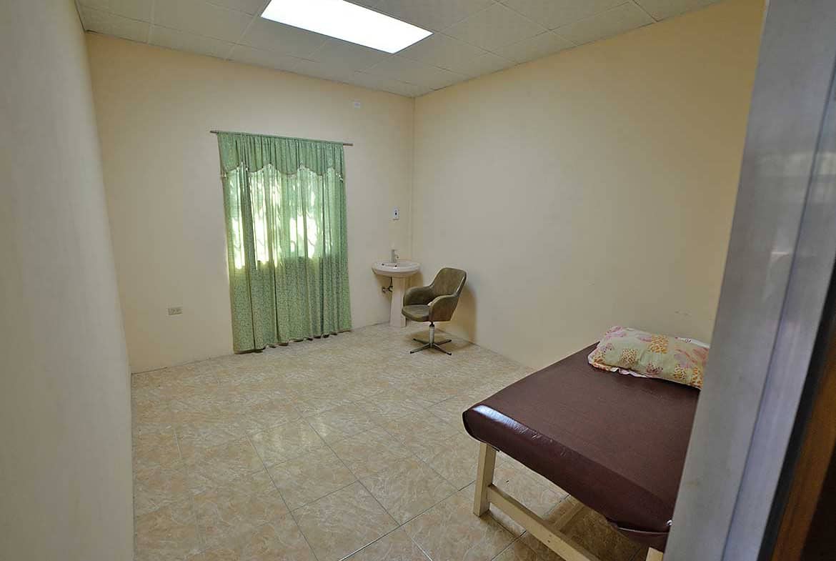 Cornerstone- Basic room with bed, window, and small desk in a healthcare facility.