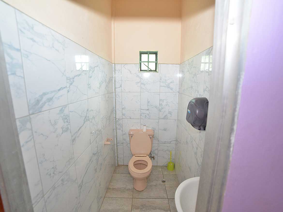 Clean Restroom with Toilet and Small Window Cornerstone- Small bathroom with toilet, wall-mounted paper towel dispenser, and window.