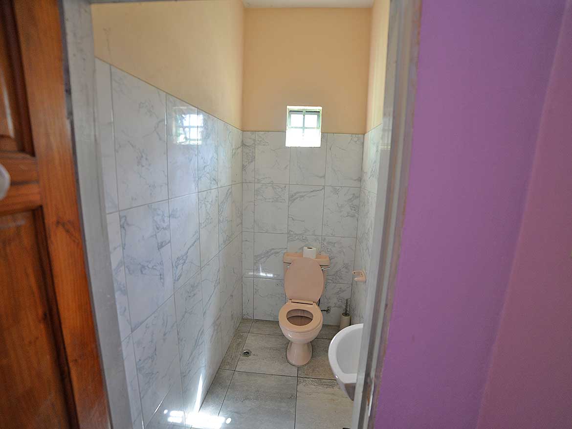 Small Bathroom with Toilet and Window Cornerstone- Compact bathroom with toilet, small window, and tiled walls.