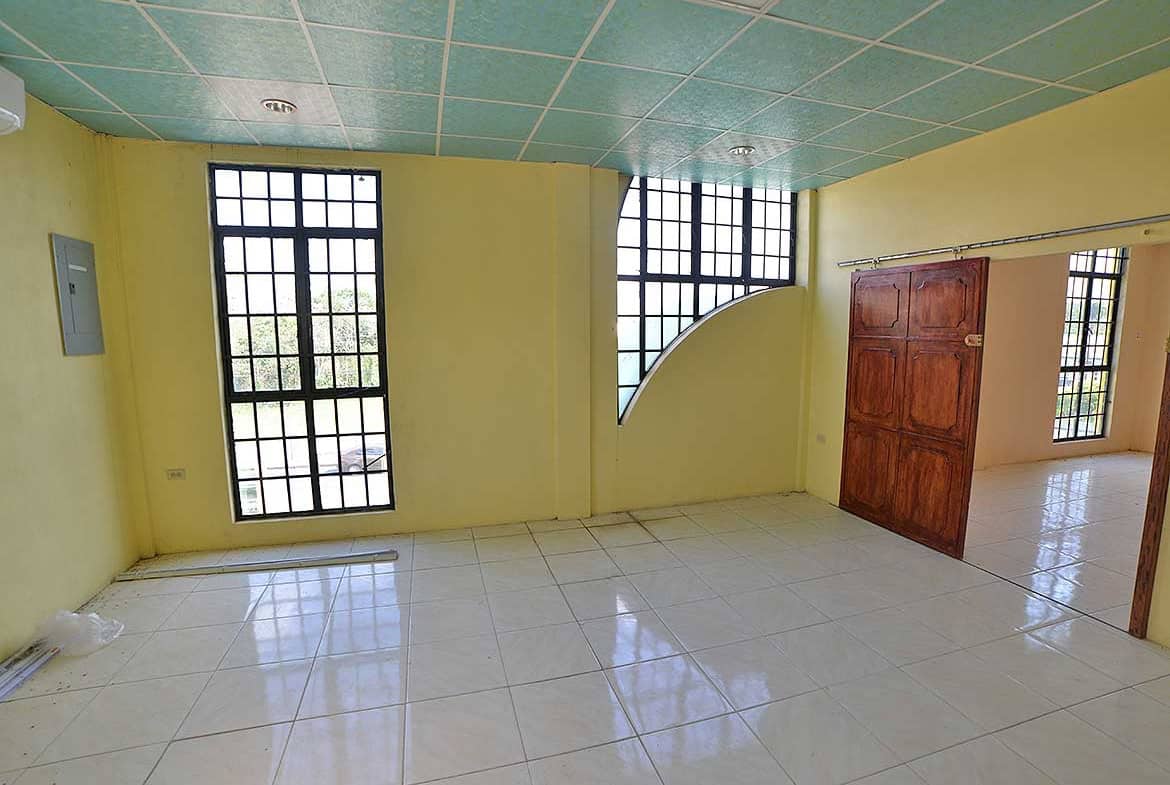 Cornerstone- Bright empty room with large windows and tiled floor in Bonne Aventure Road.