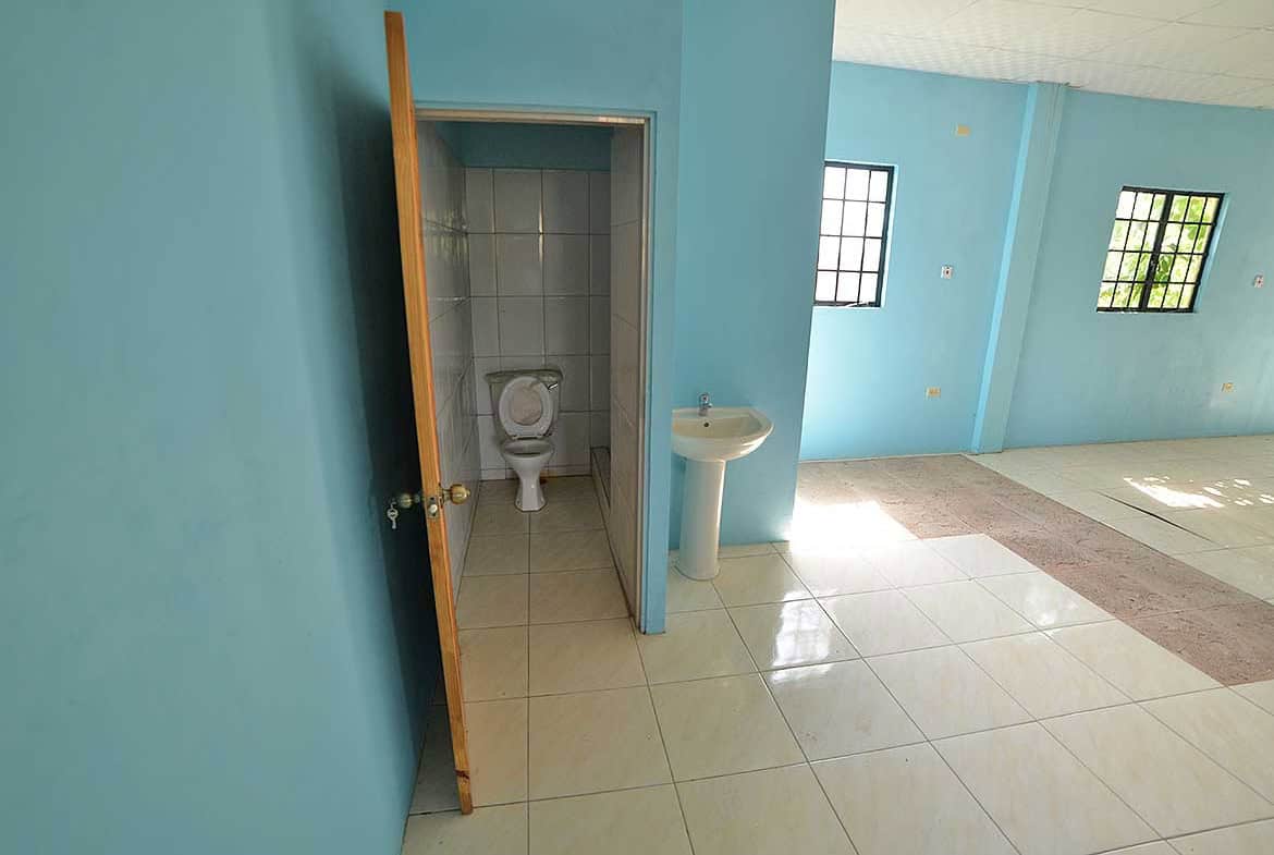 Cornerstone- Clean restroom with toilet and sink in a bright blue room.