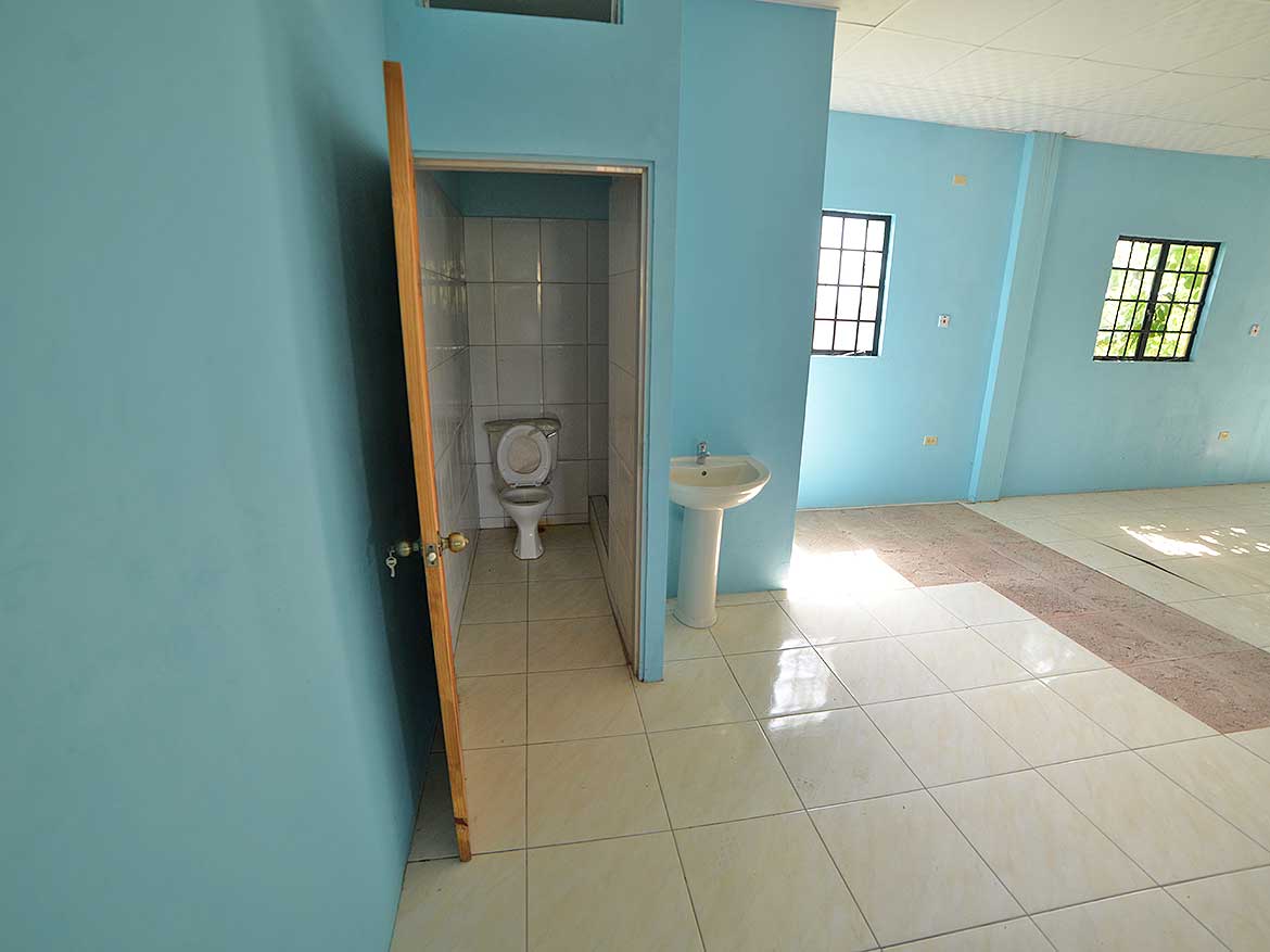 Cornerstone™ Restroom Facility Cornerstone- Clean restroom with toilet and sink in a bright blue room.