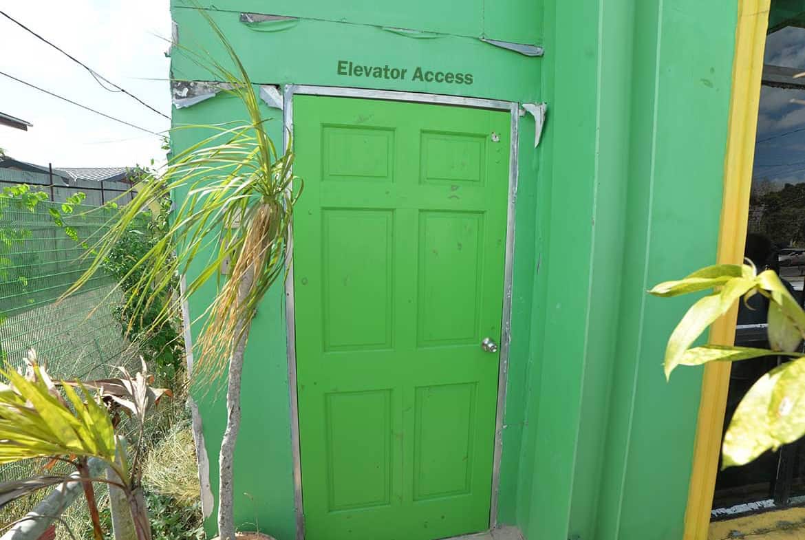 Cornerstone- Bright green elevator access door with sign above for entry.