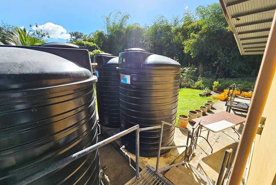 Cornerstone- Large black water storage tanks in a lush outdoor setting.