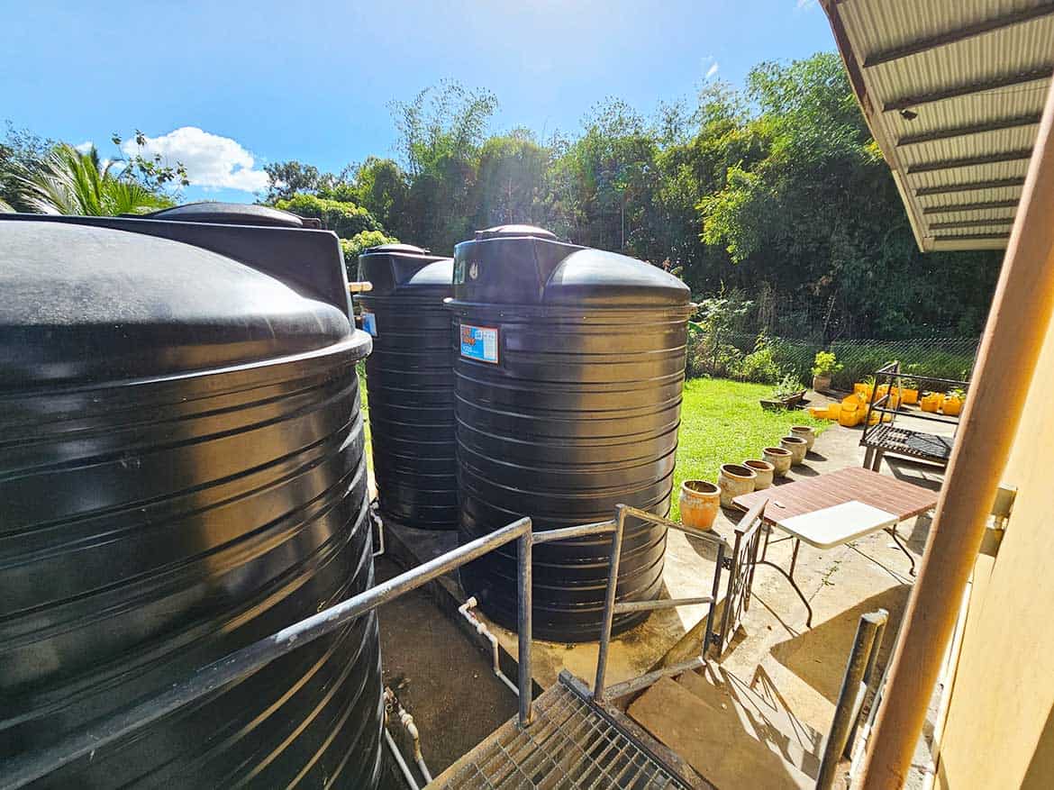 Water Storage Tanks at Cornerstone Cornerstone- Large black water storage tanks in a lush outdoor setting.