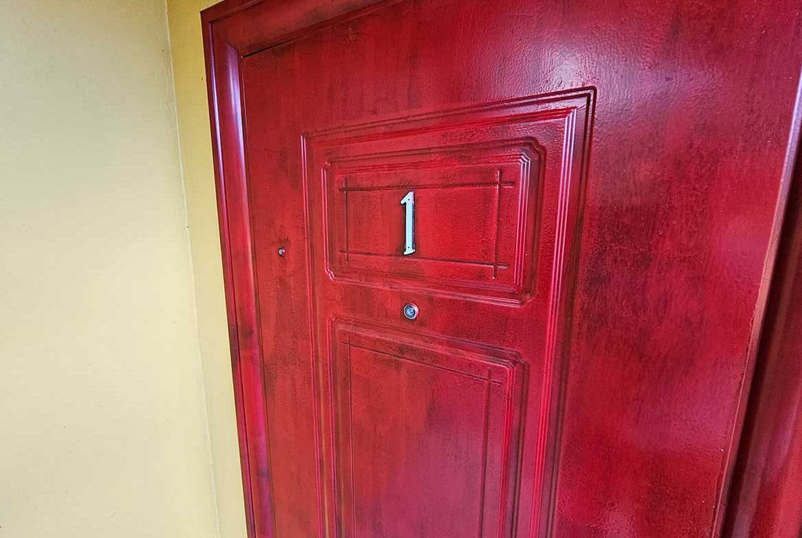 Cornerstone- Red apartment door with number 1 at Calcutta Road, Cornerstone.