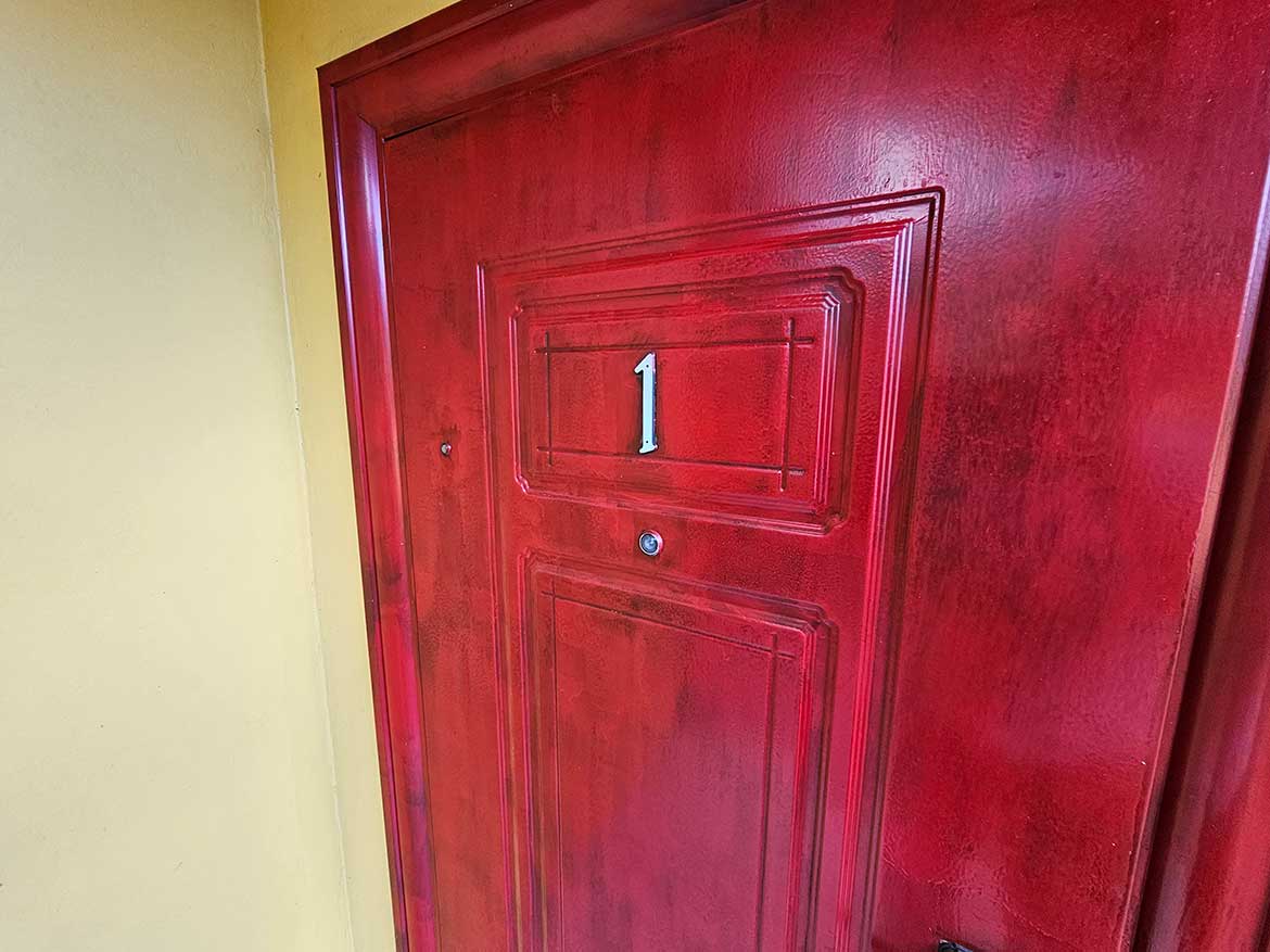 Calcutta Road Apt 1 Entrance Door Cornerstone- Red apartment door with number 1 at Calcutta Road, Cornerstone.