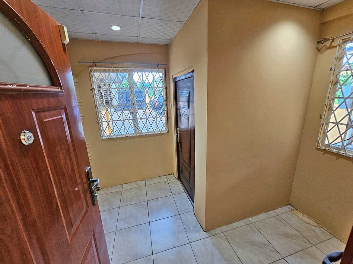 Calcutta Road Apt 1 Entrance Cornerstone- Interior view of Calcutta Road Apt 1 with windows and tiled floor.