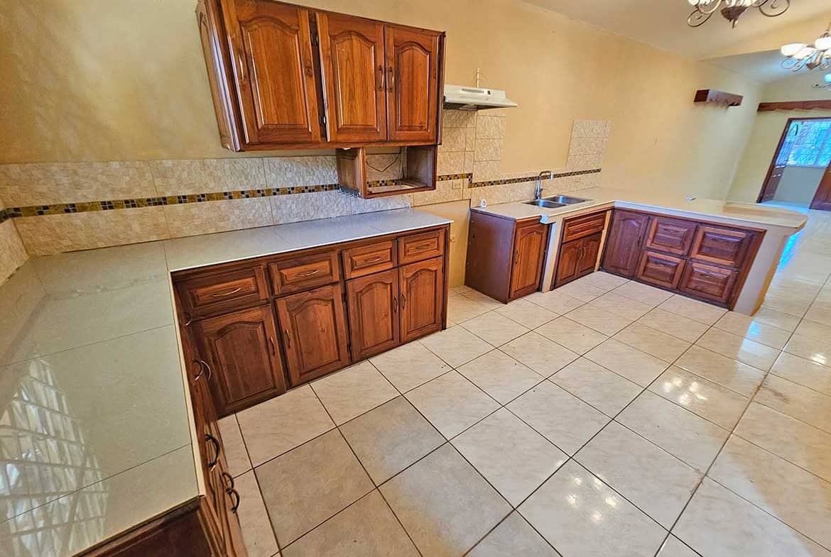 Cornerstone- Bright kitchen with wooden cabinets, tiled floor, and modern fixtures.