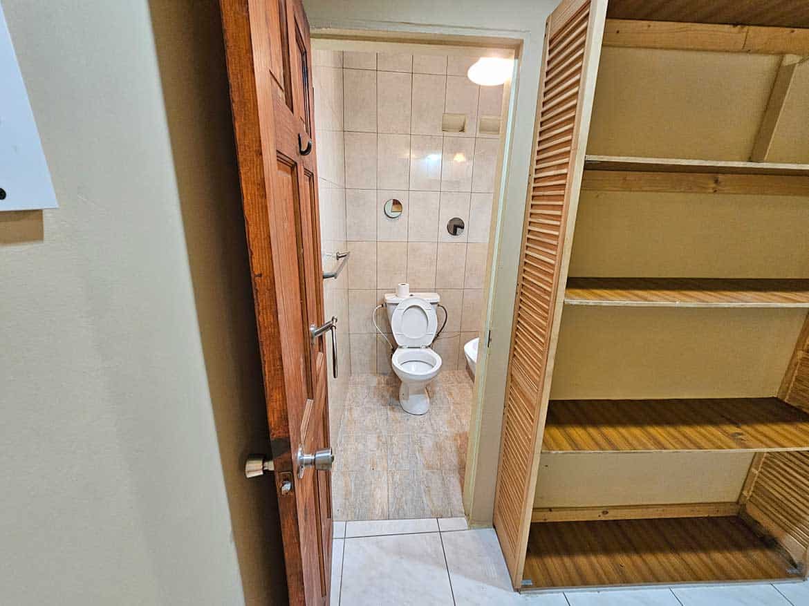 Small Bathroom with Wooden Shelves Cornerstone- Compact bathroom with toilet and wooden storage shelves in a residential space.