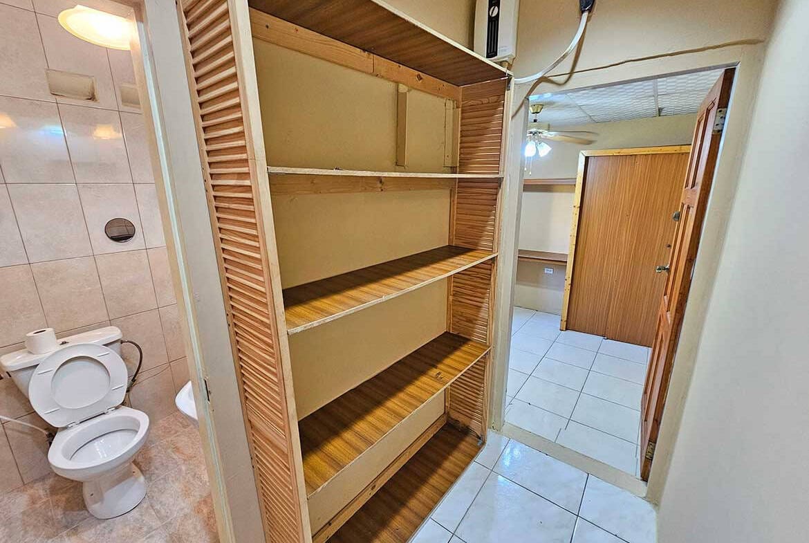 Cornerstone- Wooden storage shelf in apartment with bathroom nearby.