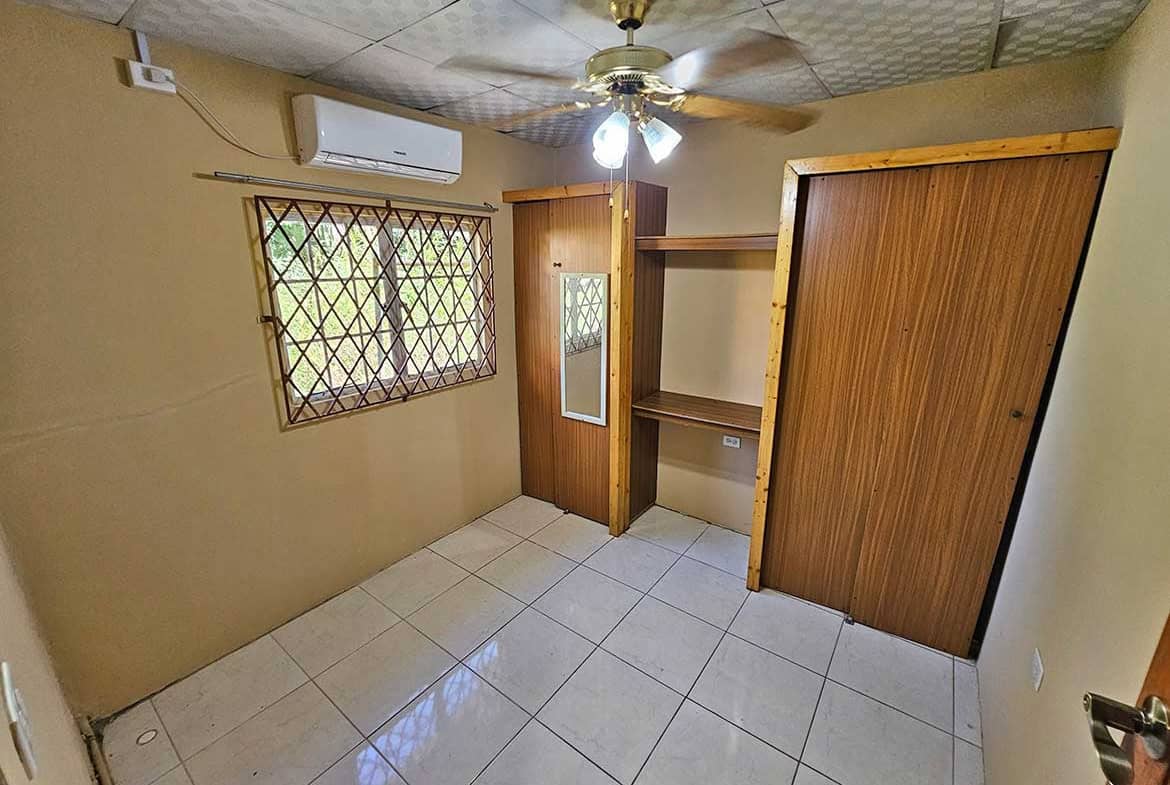 Cornerstone- Interior view of a small room with window, ceiling fan, and wooden closet.