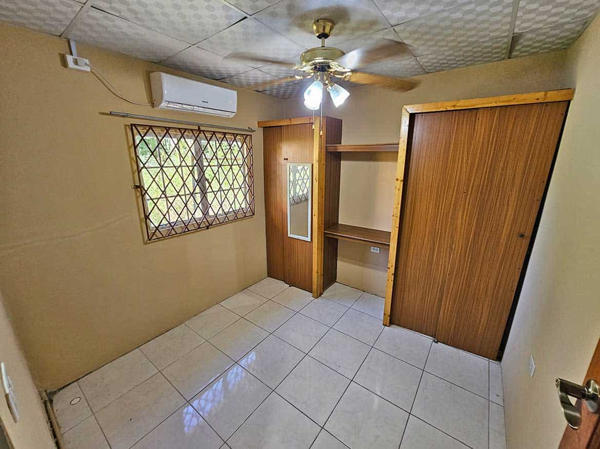 Calcutta Road Apt 1 Interior Cornerstone- Interior view of a small room with window, ceiling fan, and wooden closet.