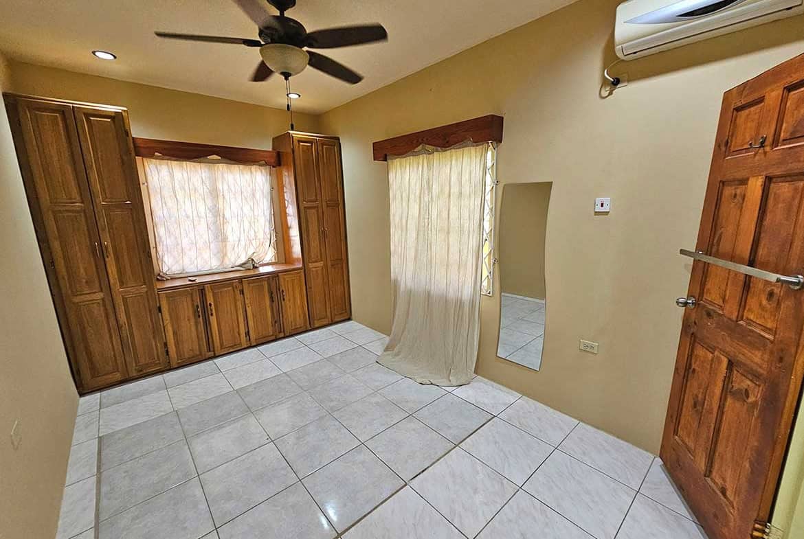 Cornerstone- Spacious room with wooden window shutters and ceiling fan in Calcutta Road Apt 1.