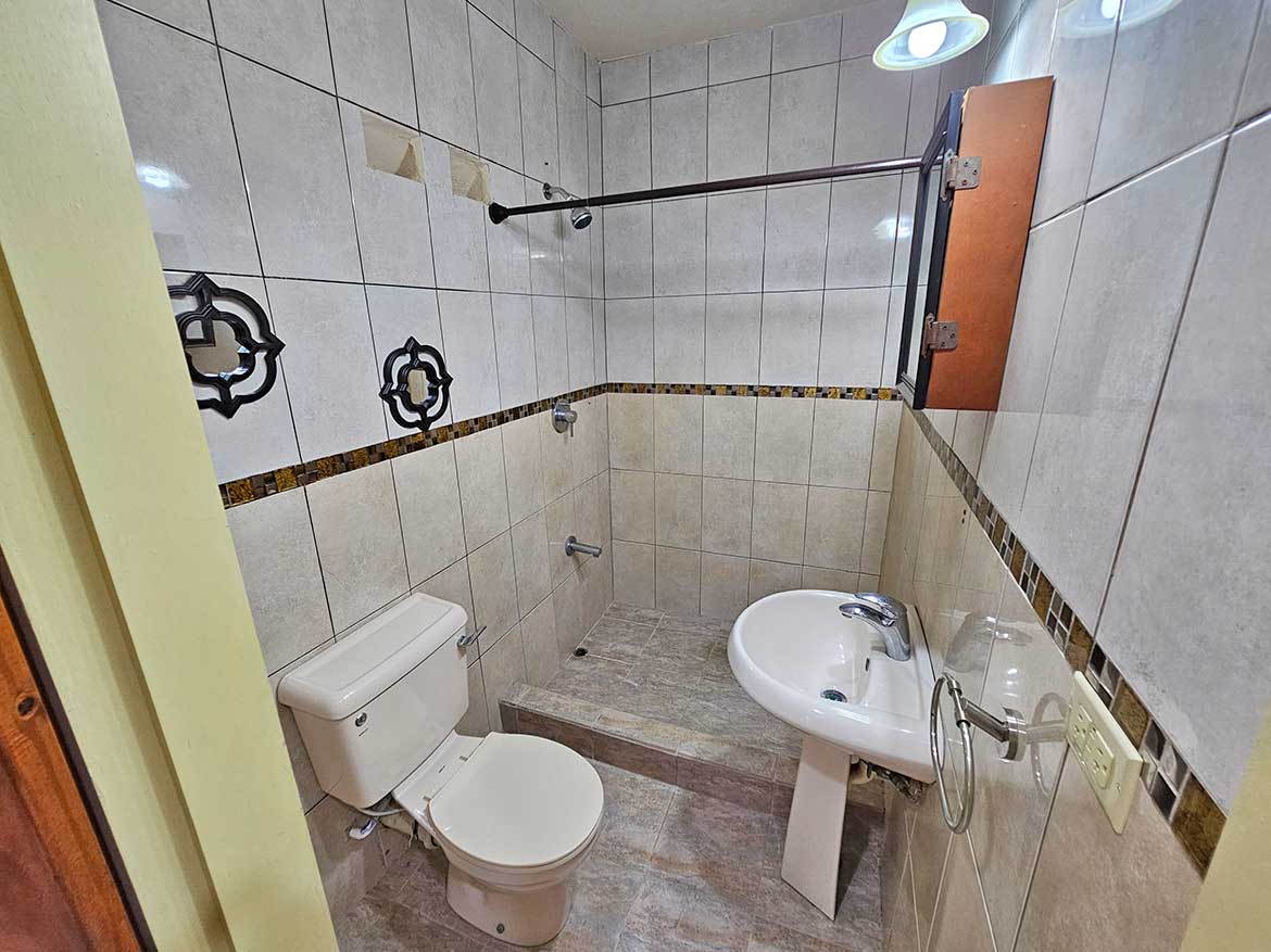 Small bathroom with toilet and sink Cornerstone- Compact bathroom with toilet, sink, and tiled walls and floor.