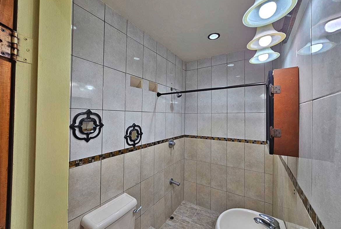 Cornerstone- Contemporary bathroom with stylish lighting and tiled walls.