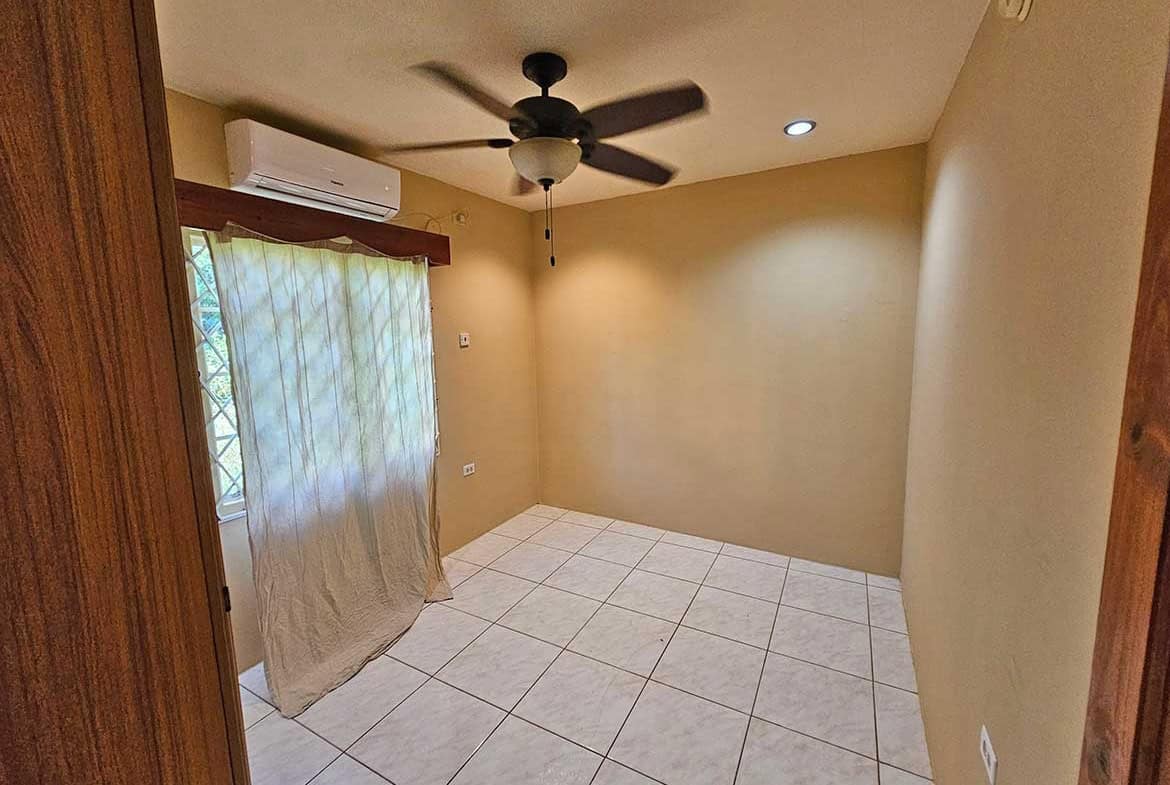 Cornerstone- Empty room with ceiling fan, air conditioner, and window with curtains.