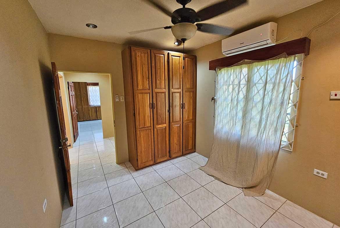Cornerstone- Spacious room with wooden wardrobe, ceiling fan, and air conditioner.