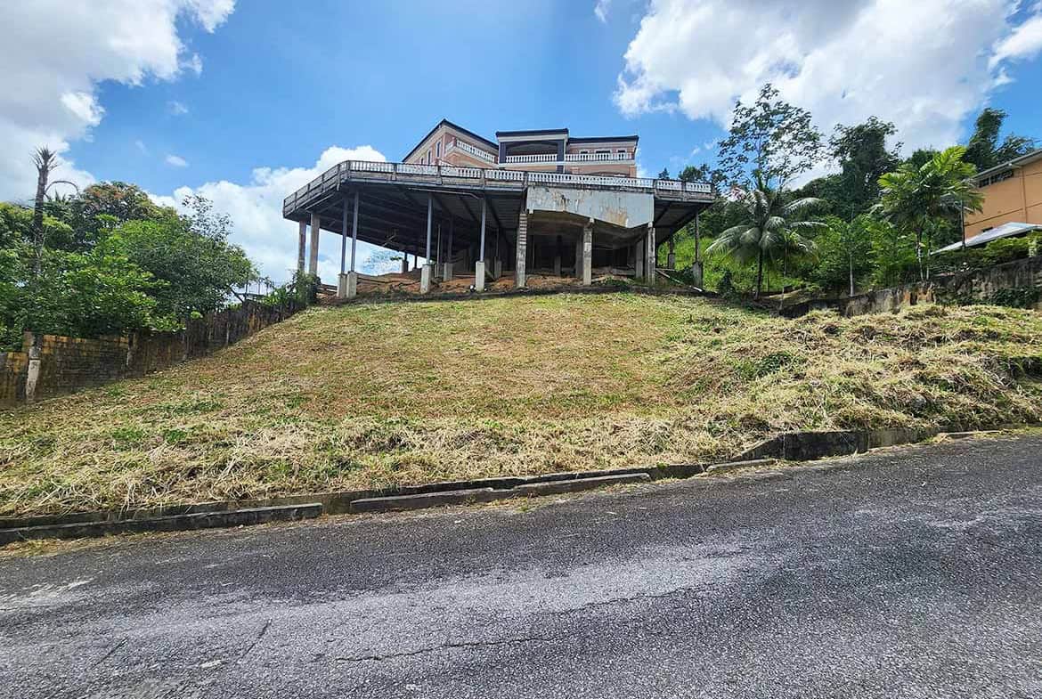 Cornerstone- Modern house on a hill with a large deck and lush greenery.