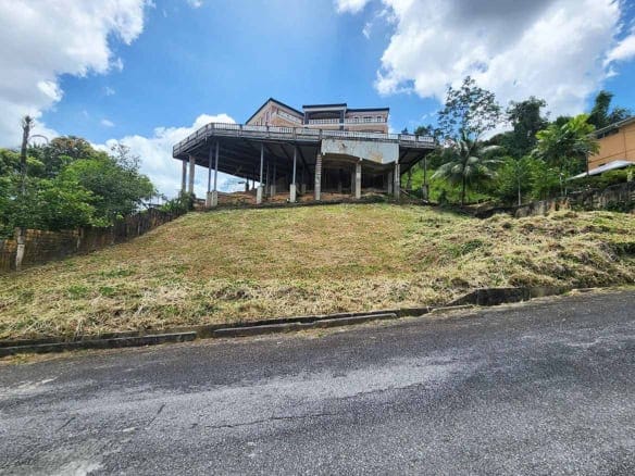 Cornerstone- Modern house on a hill with a large deck and lush greenery.
