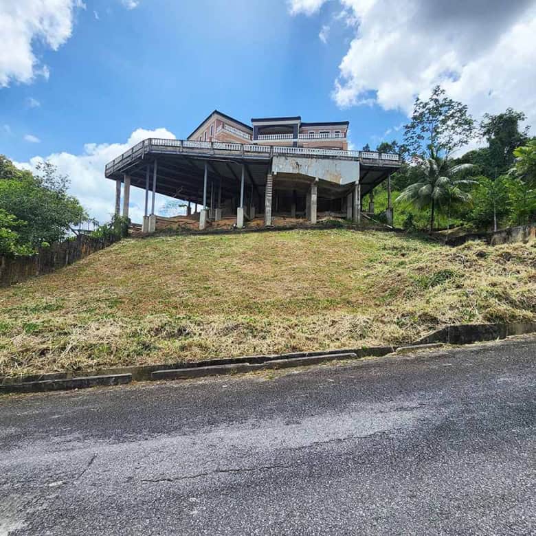 Cornerstone- Modern house on a hill with a large deck and lush greenery.