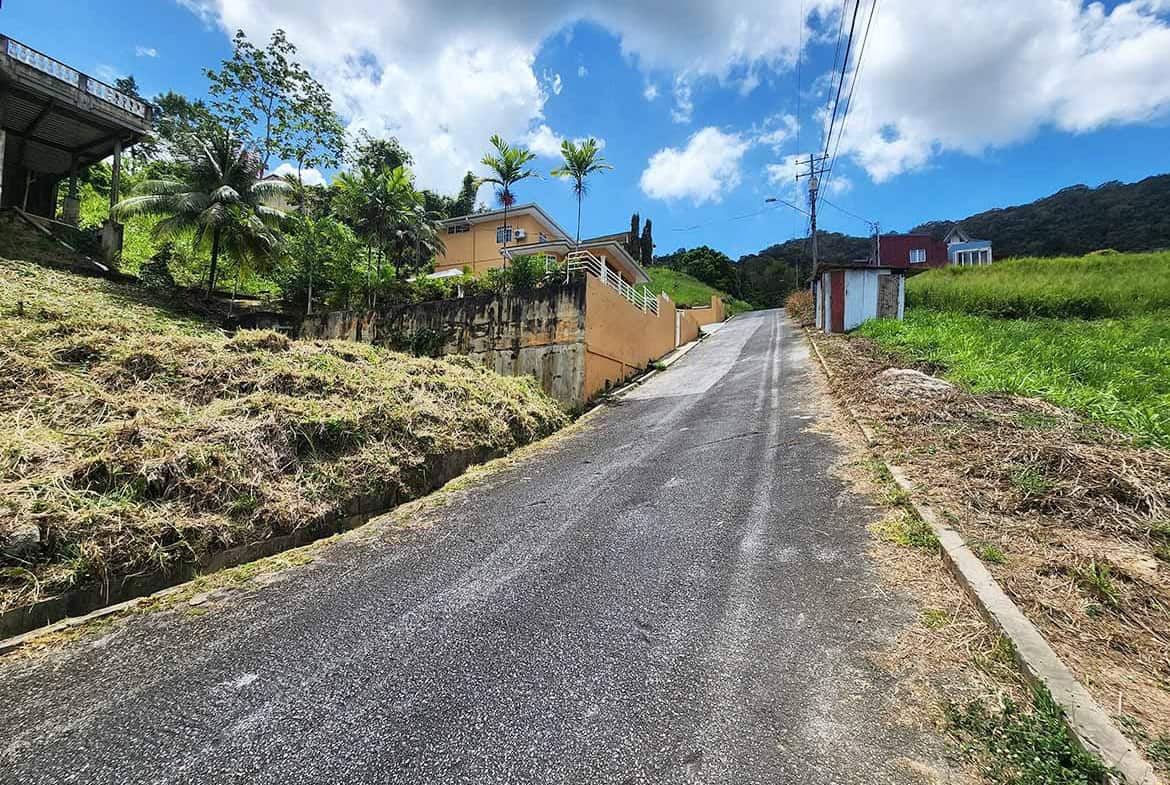 Cornerstone- Steep residential road in Graceland Heights with houses and lush greenery.
