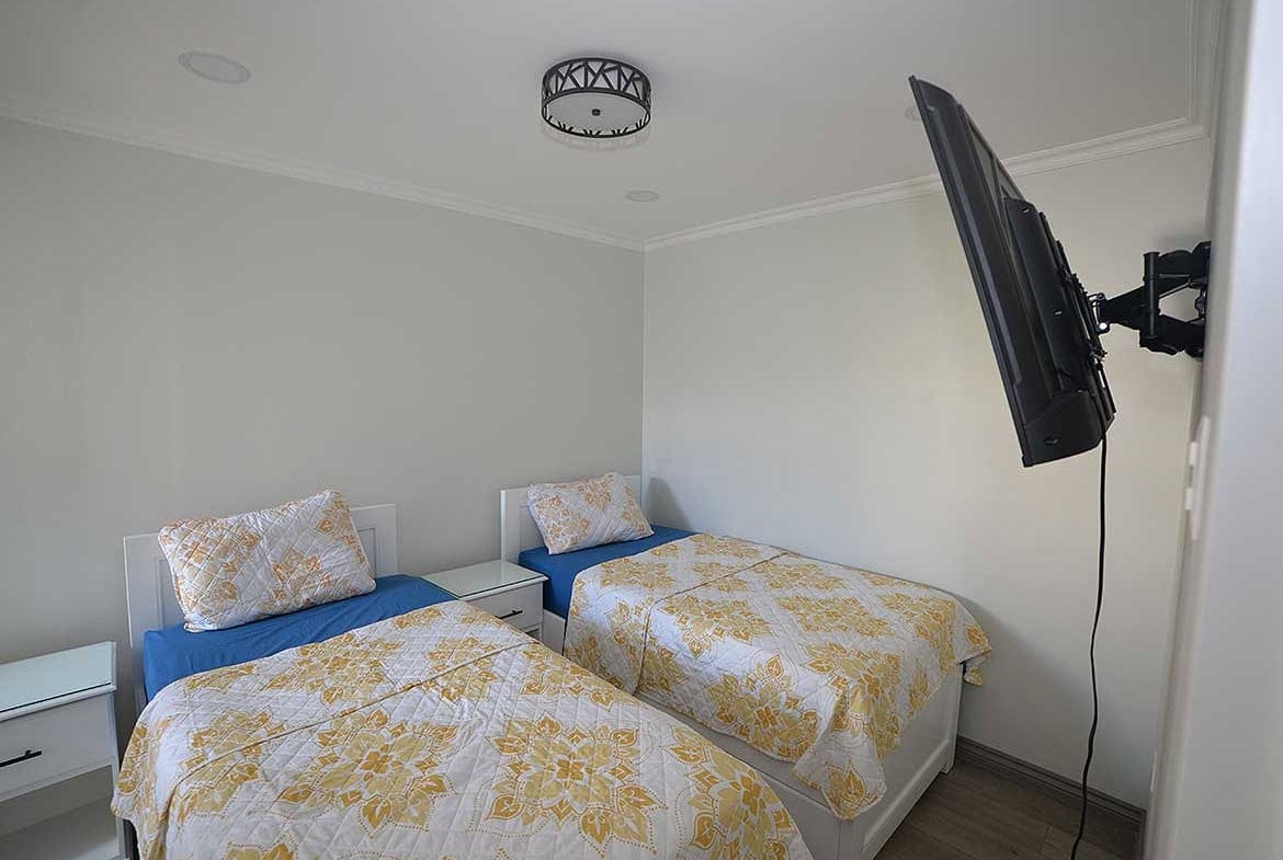 Cornerstone- Cozy 1-bedroom apartment with twin beds and wall-mounted TV.