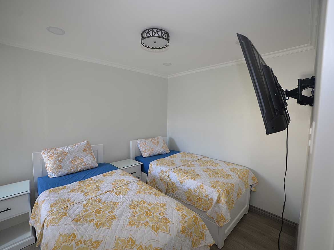 Modern 1-Bedroom Apartment Interior Cornerstone- Cozy 1-bedroom apartment with twin beds and wall-mounted TV.