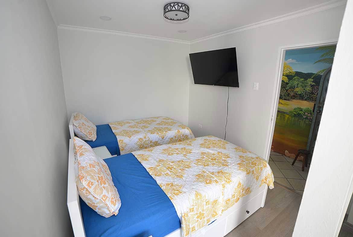 Cornerstone- Comfortable bedroom with twin beds, colorful bedding, and a wall-mounted TV.