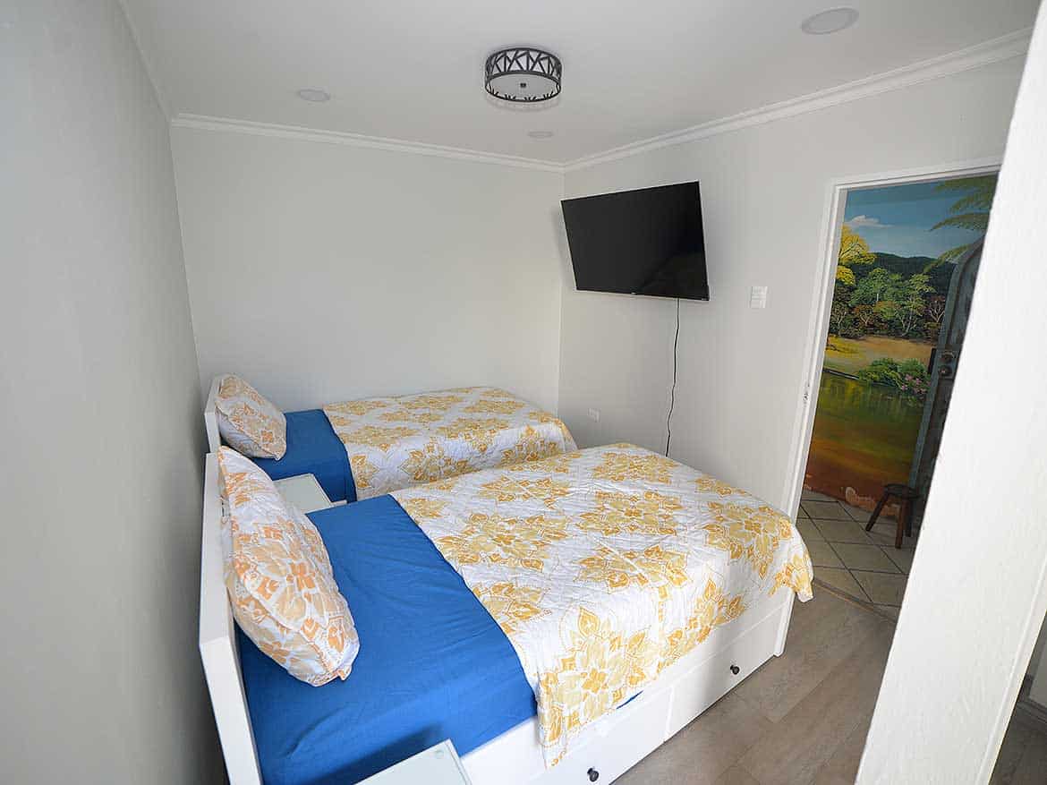 Cozy Bedroom in 1-Bedroom Apartment Cornerstone- Comfortable bedroom with twin beds, colorful bedding, and a wall-mounted TV.